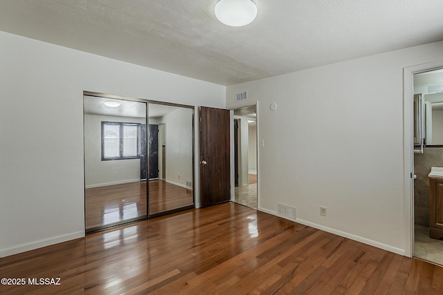 6158 E Calle Aurora, Tucson, AZ 85711 - unfurnished bedroom with wood-type flooring, a closet, baseboards, and ensuite bathroom
