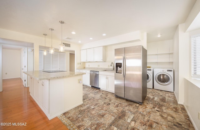 9846 E 2nd St, Tucson, AZ 85748 - kitchen with appliances with stainless steel finishes, a sink, white cabinetry, washer and clothes dryer, and a center island
