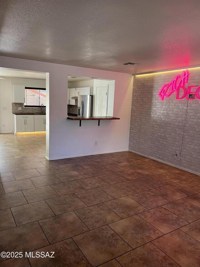 1558 E Los Cabos Pl, Tucson, AZ 85706 - empty room with brick wall, a textured ceiling, and a sink
