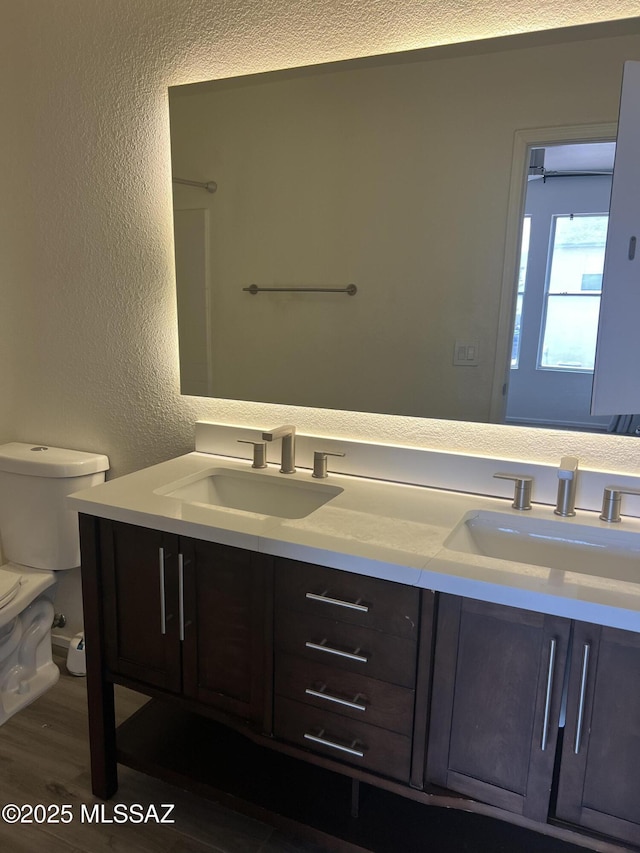 1558 E Los Cabos Pl, Tucson, AZ 85706 - full bathroom featuring a textured wall, toilet, double vanity, and wood finished floors
