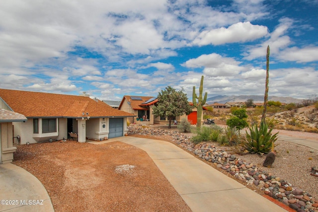 10095 E Autumnwind Pl, Tucson, AZ 85730 - view of front of property featuring concrete driveway, a garage, stucco siding, a mountain view, and solar panels