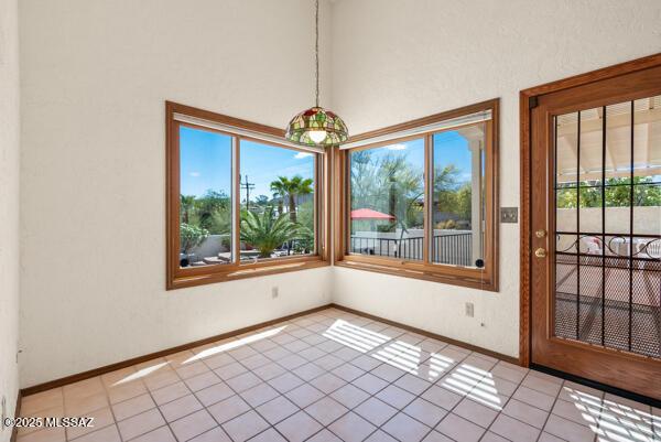 1861 N Camino Claveles, Tucson, AZ 85745 - unfurnished dining area with light tile patterned floors, baseboards, and a high ceiling