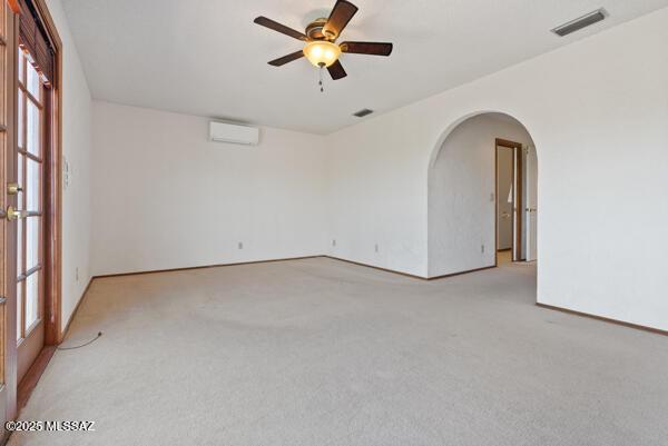 1861 N Camino Claveles, Tucson, AZ 85745 - empty room with an AC wall unit, arched walkways, ceiling fan, light carpet, and baseboards