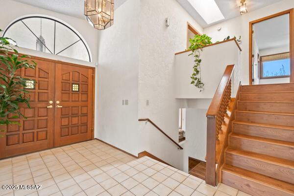 1861 N Camino Claveles, Tucson, AZ 85745 - tiled foyer entrance featuring stairway, a skylight, and a chandelier