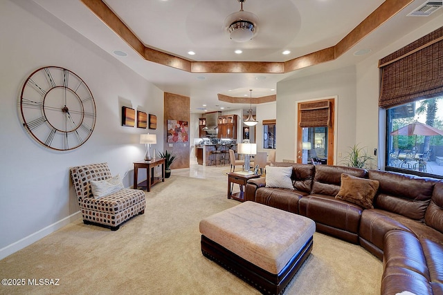 living area with light carpet, recessed lighting, baseboards, a raised ceiling, and a ceiling fan