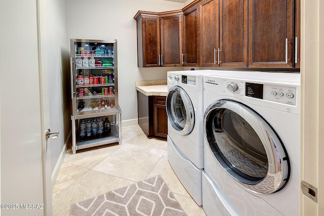 clothes washing area featuring separate washer and dryer, cabinet space, baseboards, and light tile patterned floors