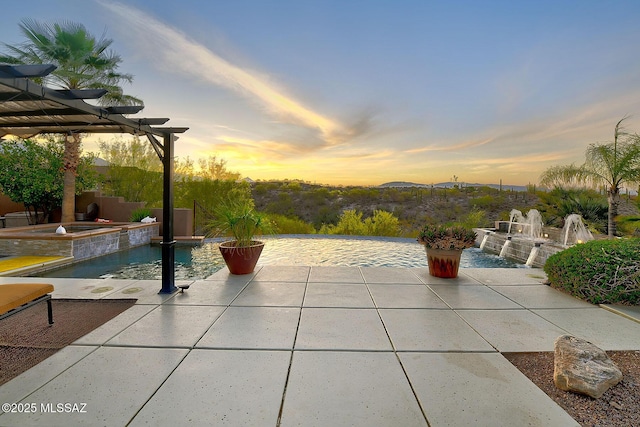 patio terrace at dusk featuring a pool with connected hot tub