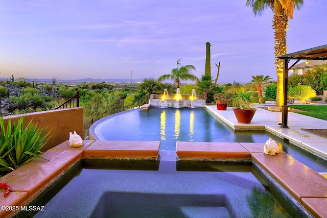 pool at dusk featuring a patio area and a pool with connected hot tub