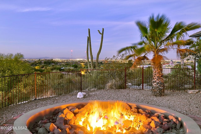 patio terrace at dusk featuring a fire pit and fence