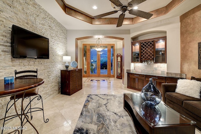 living area with arched walkways, a ceiling fan, and bar area