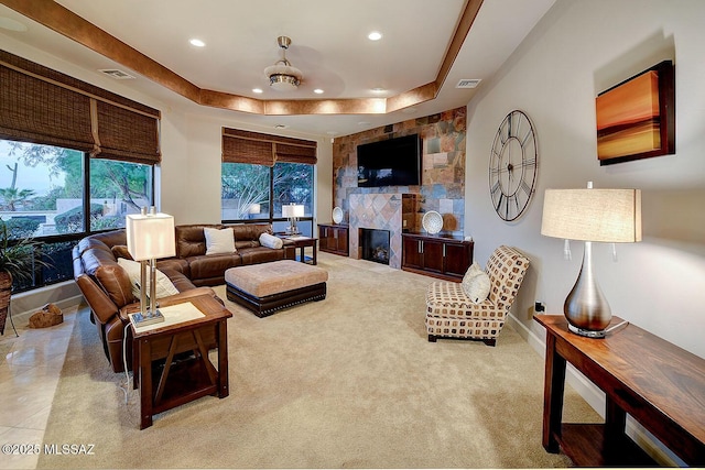 living room with a raised ceiling, recessed lighting, and a large fireplace