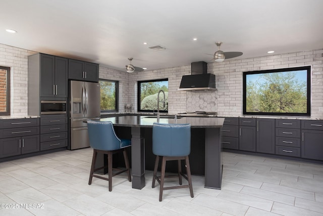 2360 S Camino Del Sol, Green Valley, AZ 85622 - kitchen with wall chimney exhaust hood, stainless steel appliances, a sink, a ceiling fan, and a kitchen bar