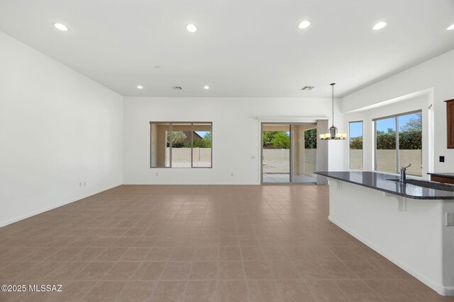 62742 E Oakwood Dr, Saddlebrooke, AZ 85739 - unfurnished living room with a chandelier, recessed lighting, a sink, and baseboards