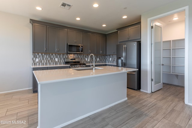 9734 E Miller Peak Trl, Tucson, AZ 85747 - kitchen with stainless steel appliances, a sink, light countertops, decorative backsplash, and a kitchen island with sink
