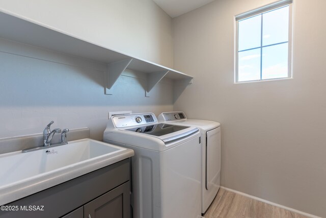 9734 E Miller Peak Trl, Tucson, AZ 85747 - laundry area with washer and clothes dryer, light wood-type flooring, cabinet space, and baseboards