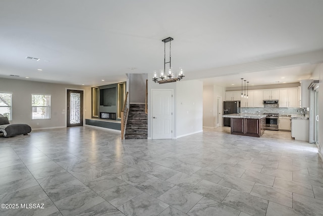3526 E Farrier Dr, Tucson, AZ 85739 - unfurnished living room featuring light marble finish floors, baseboards, recessed lighting, a sink, and a chandelier