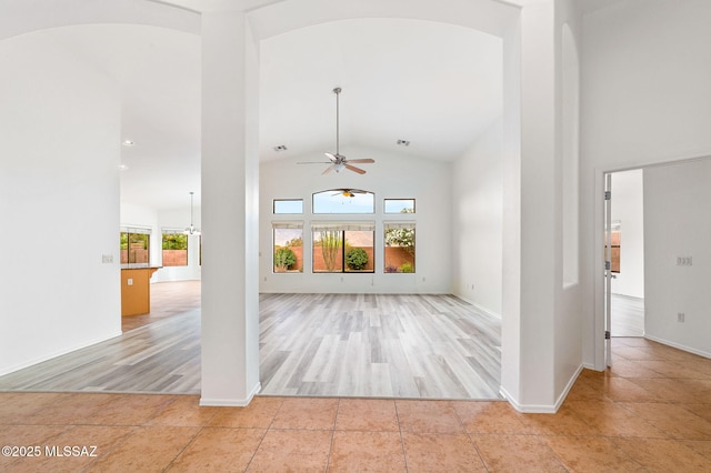 11874 N Verismo Dr, Tucson, AZ 85737 - unfurnished living room with a ceiling fan, lofted ceiling, light wood finished floors, baseboards, and arched walkways