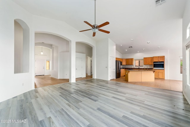 11874 N Verismo Dr, Tucson, AZ 85737 - unfurnished living room with a ceiling fan, light wood-type flooring, high vaulted ceiling, recessed lighting, and arched walkways