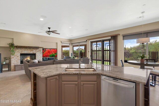 1808 W Quartz Rock Pl, Tucson, AZ 85737 - kitchen with stainless steel dishwasher, a sink, an island with sink, light stone counters, and decorative light fixtures