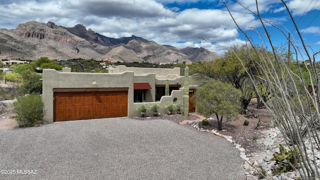7020 N Chaparral Ave, Tucson, AZ 85718 - pueblo-style home with an attached garage, stucco siding, a chimney, gravel driveway, and a mountain view
