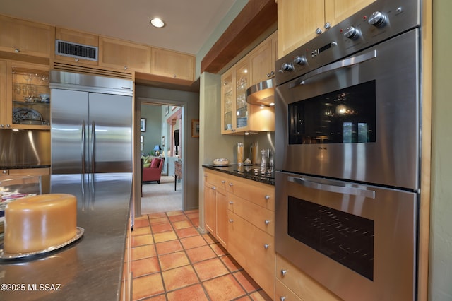 7020 N Chaparral Ave, Tucson, AZ 85718 - kitchen featuring appliances with stainless steel finishes, light brown cabinets, glass insert cabinets, recessed lighting, and dark stone counters