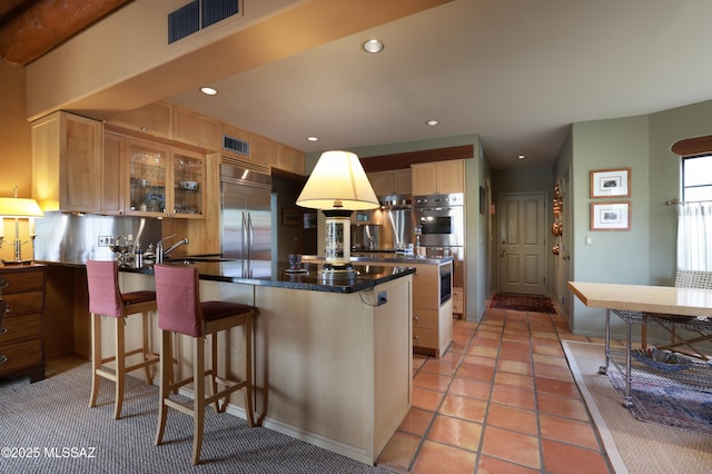 7020 N Chaparral Ave, Tucson, AZ 85718 - kitchen featuring stainless steel appliances, a peninsula, glass insert cabinets, a breakfast bar area, and recessed lighting