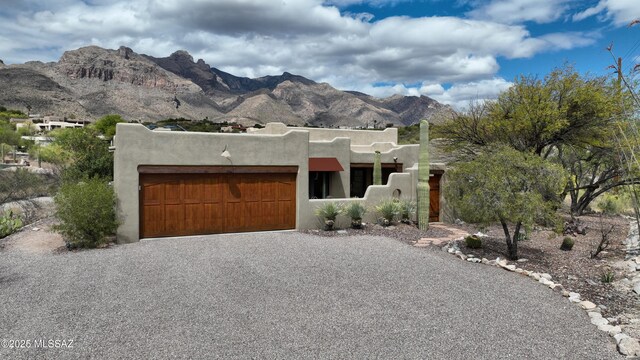 7020 N Chaparral Ave, Tucson, AZ 85718 - pueblo-style house featuring driveway, an attached garage, stucco siding, and a mountain view