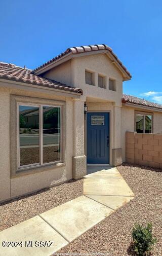 view of front of home featuring a tile roof, fence, and stucco siding