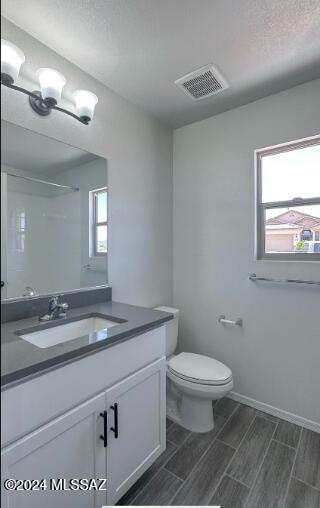 full bath with toilet, vanity, and wood tiled floors