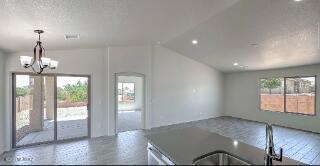 unfurnished living room featuring healthy amount of natural light, a chandelier, a sink, and recessed lighting