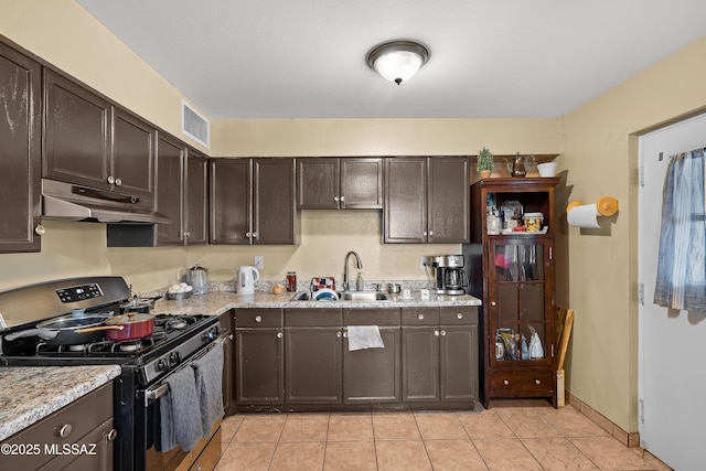 4760 W Tumacacori Dr, Amado, AZ 85645 - kitchen with gas stove, under cabinet range hood, a sink, dark brown cabinetry, and light tile patterned floors