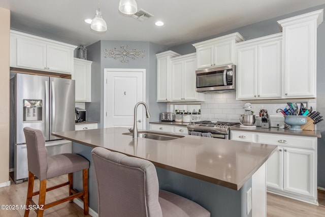 14247 E Axle Dr, Vail, AZ 85641 - kitchen with stainless steel appliances, a sink, a kitchen bar, light wood-style floors, and backsplash