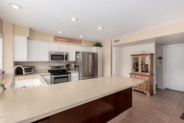 681 W Mountain Ridge Dr, Oro Valley, AZ 85737 - kitchen with appliances with stainless steel finishes, a sink, a peninsula, light tile patterned floors, and recessed lighting