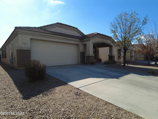 6700 S Stone Fly Dr, Tucson, AZ 85757 - view of front of home with concrete driveway, an attached garage, a tile roof, and stucco siding