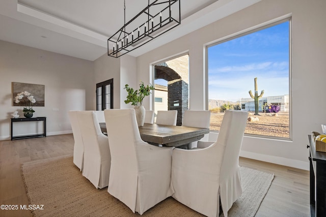 dining area with light wood-style floors, baseboards, and a chandelier