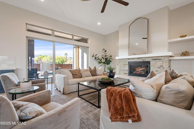 living room featuring a stone fireplace, ceiling fan, recessed lighting, and a towering ceiling