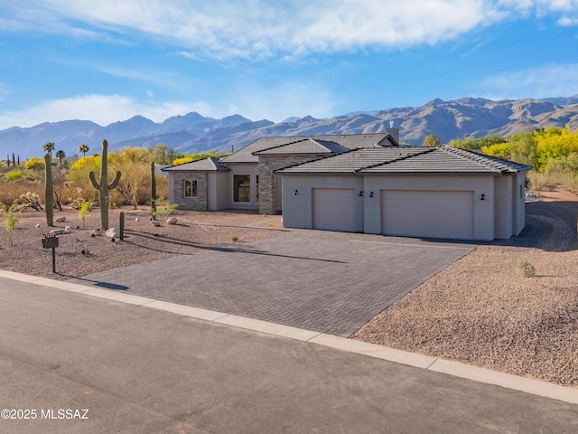 view of front of house with a mountain view, decorative driveway, a garage, and stone siding