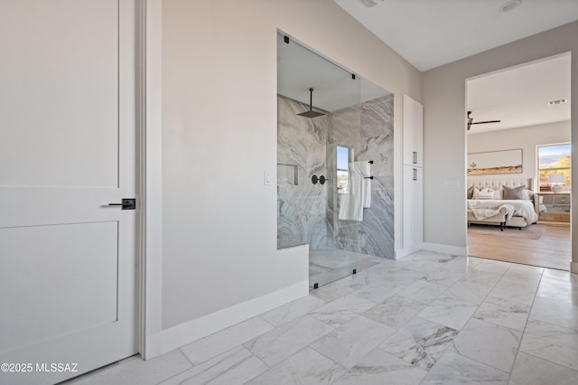 ensuite bathroom with a marble finish shower, marble finish floors, baseboards, and a ceiling fan