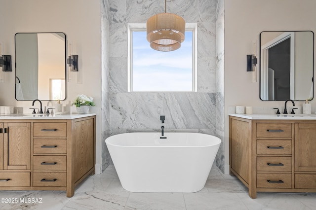 bathroom featuring marble look tiles, a soaking tub, and two vanities