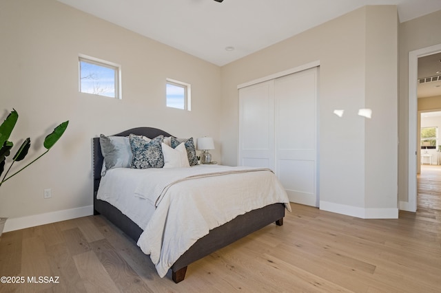 bedroom with baseboards, multiple windows, and light wood-style flooring