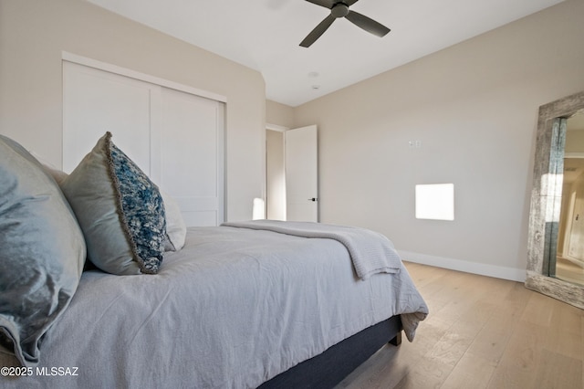 bedroom with light wood-style flooring, a closet, ceiling fan, and baseboards