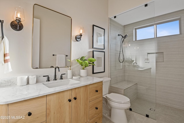 bathroom with toilet, tiled shower, vanity, and tile patterned floors
