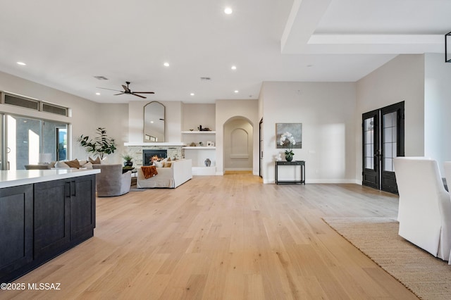 kitchen with dark cabinets, arched walkways, a ceiling fan, light wood-type flooring, and built in features