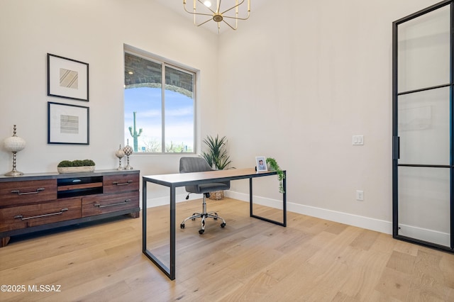 office space featuring baseboards, a chandelier, and light wood finished floors