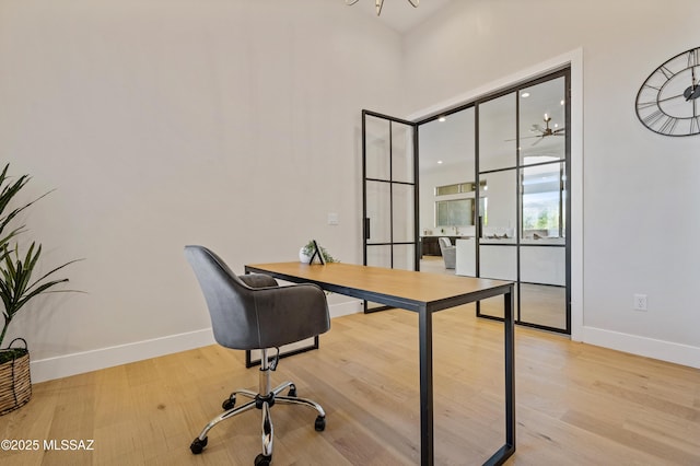 office with baseboards, wood finished floors, and a towering ceiling