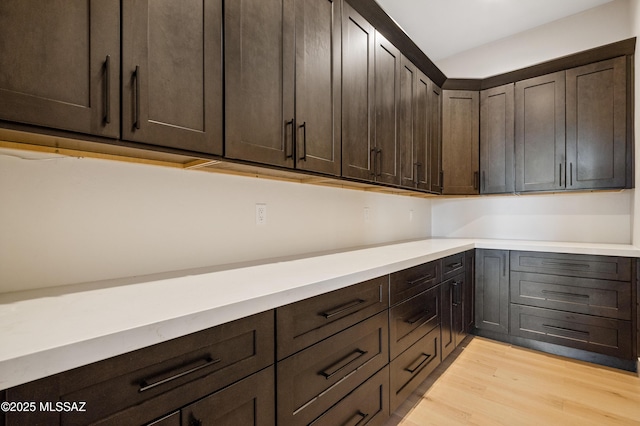 kitchen with dark brown cabinets, light wood-style flooring, and light countertops
