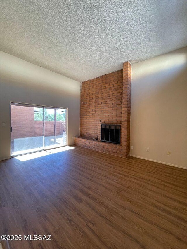 3873 N Pasatiempo Pl, Tucson, AZ 85705 - unfurnished living room with a textured ceiling, wood finished floors, and a brick fireplace