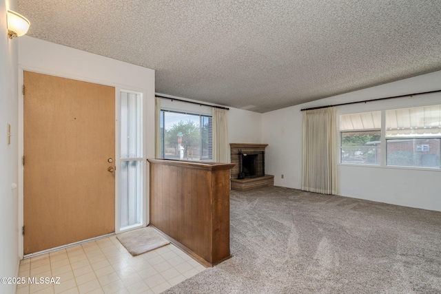 5301 E 4th St, Tucson, AZ 85711 - unfurnished living room featuring a textured ceiling, healthy amount of natural light, a fireplace, and light colored carpet