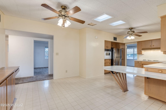 5301 E 4th St, Tucson, AZ 85711 - kitchen with white appliances, light countertops, ceiling fan, brown cabinetry, and light carpet