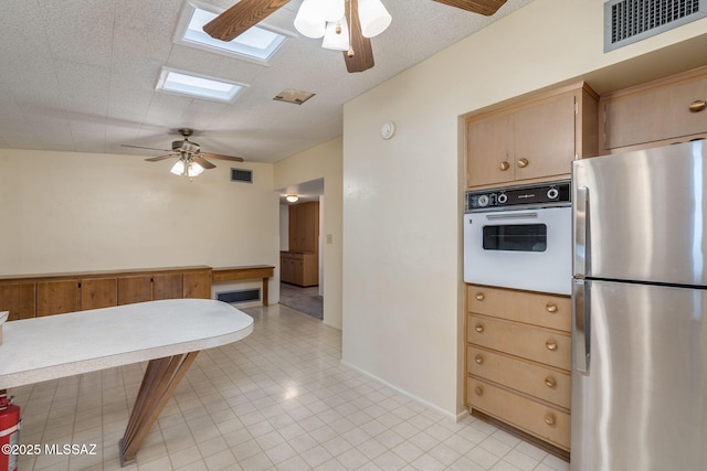 5301 E 4th St, Tucson, AZ 85711 - kitchen featuring freestanding refrigerator, white oven, a ceiling fan, a skylight, and light tile patterned floors